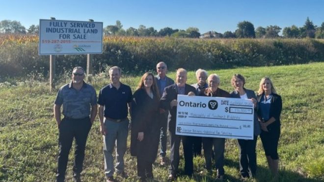 Municipal Staff Councillors and County Staff holding a cheque in front of the industrial park.